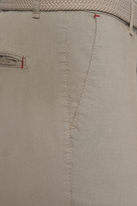 Natural beige shorts fabric close-up with stitched seam and belt-loop edge