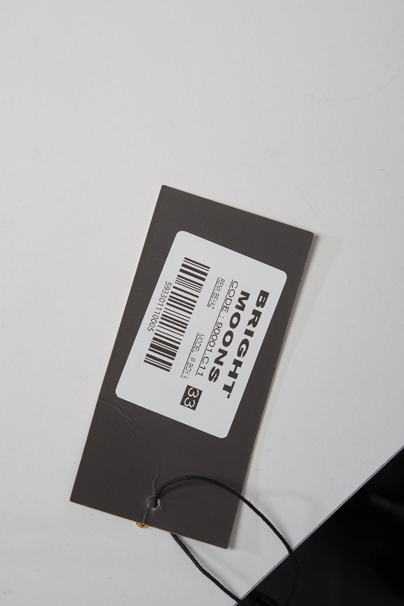 Garment price tag with barcode and brand label on black tag backing.