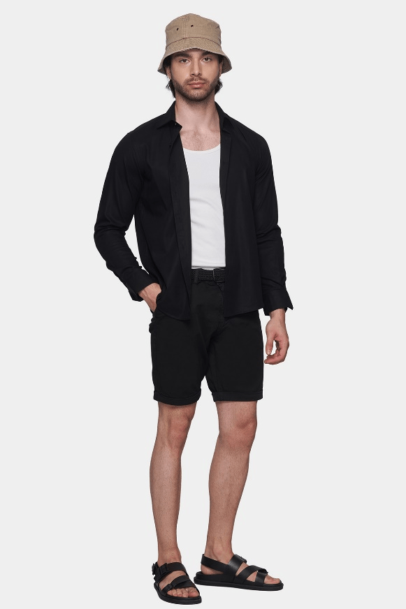 Jet black summer shorts on model, with belt loops and front fly