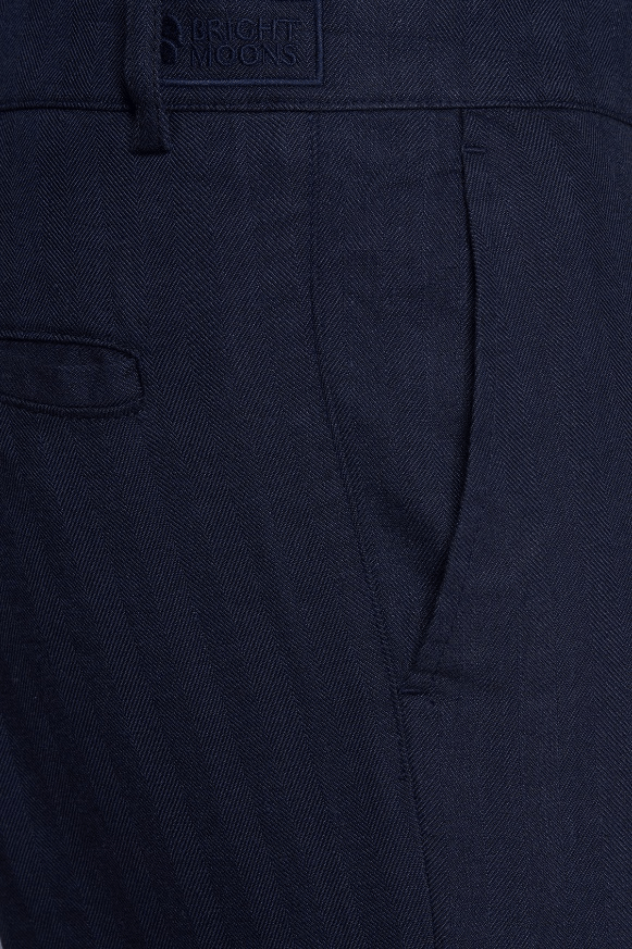 Dark navy chino pants fabric close-up with logo patch and front pleat