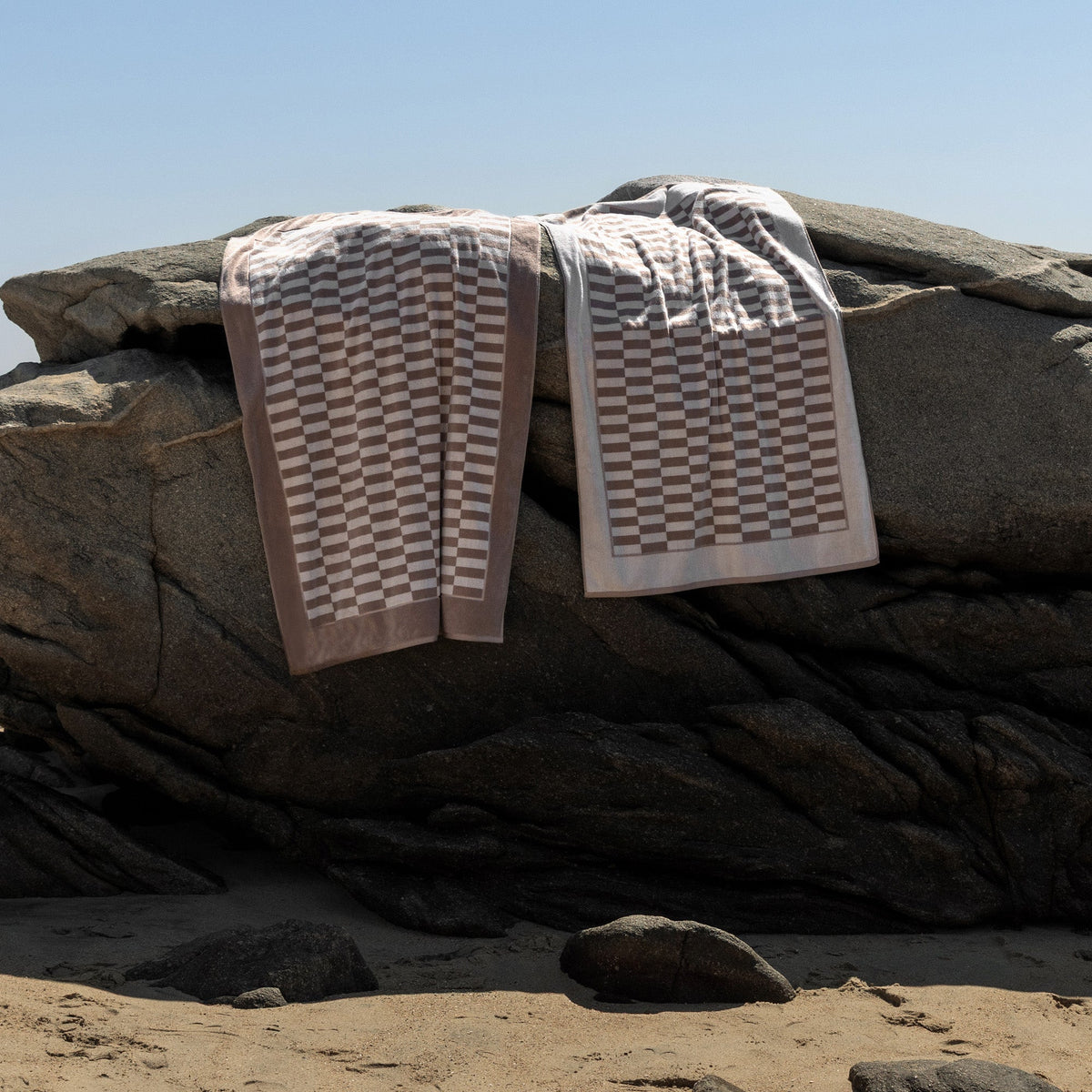Cotton towels set, taupe and white check pattern, neatly folded on a dark blanket