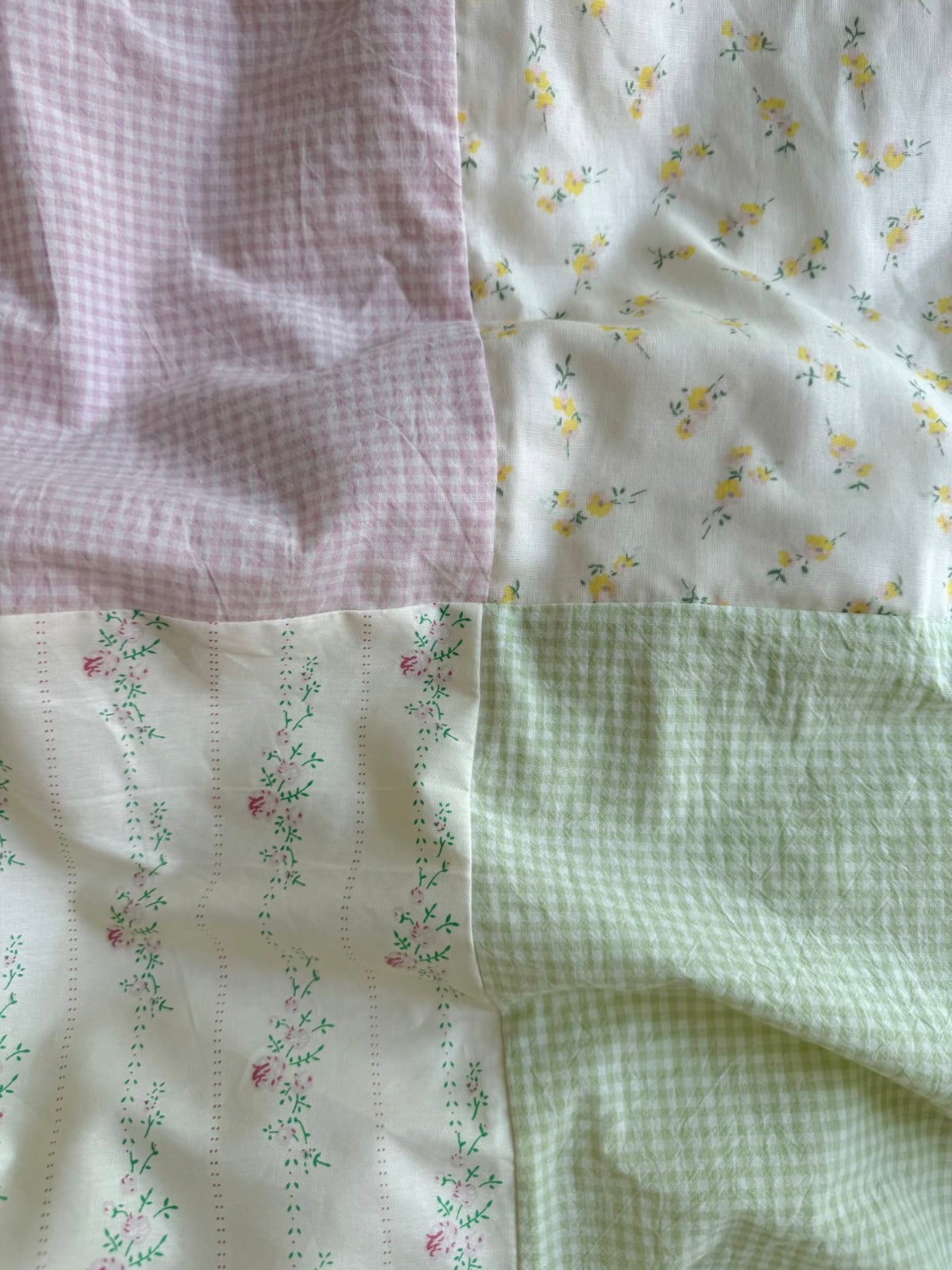 Close-up of pastel floral duvet fabric panels in pink, mint green, and white textures