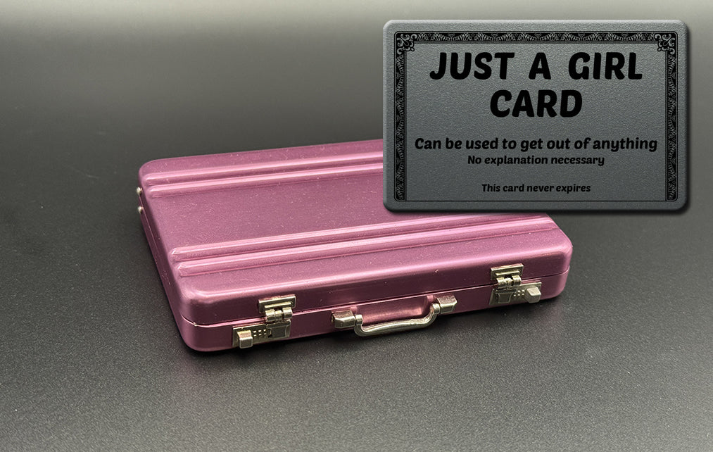 Pink mini briefcase with black “JUST A GIRL” card holder on top