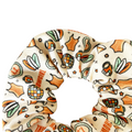 Cream fabric scrunchie with orange and green cartoon motifs