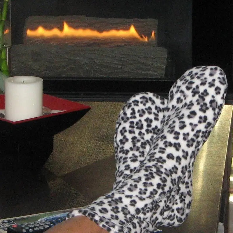 Snow leopard fleece socks worn on feet, black-and-white spotted pattern.