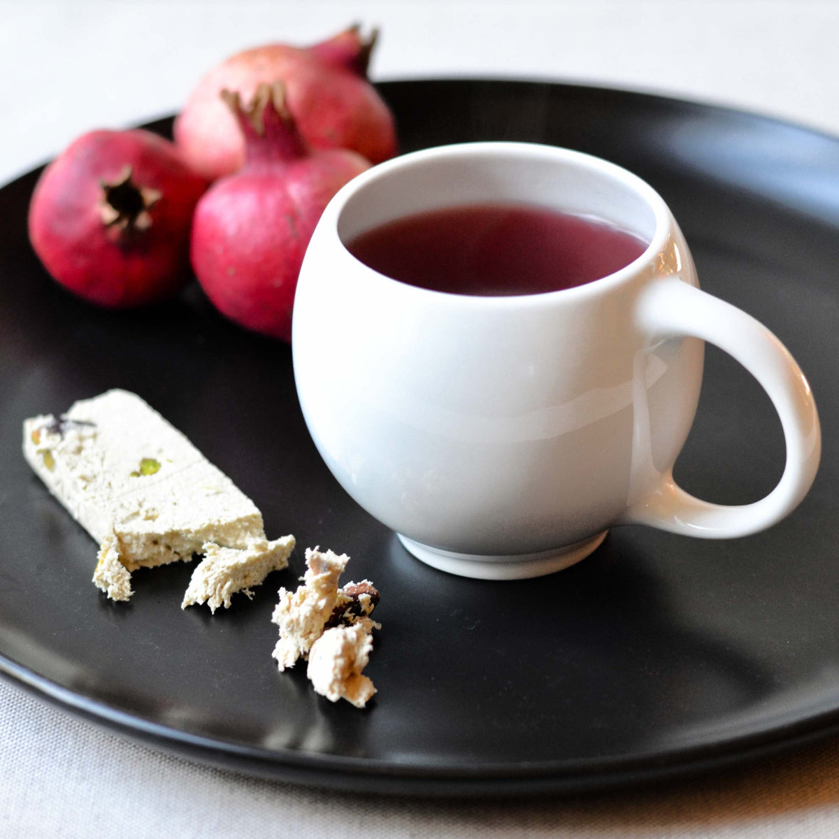 White ceramic teacup with curved handle filled with dark tea