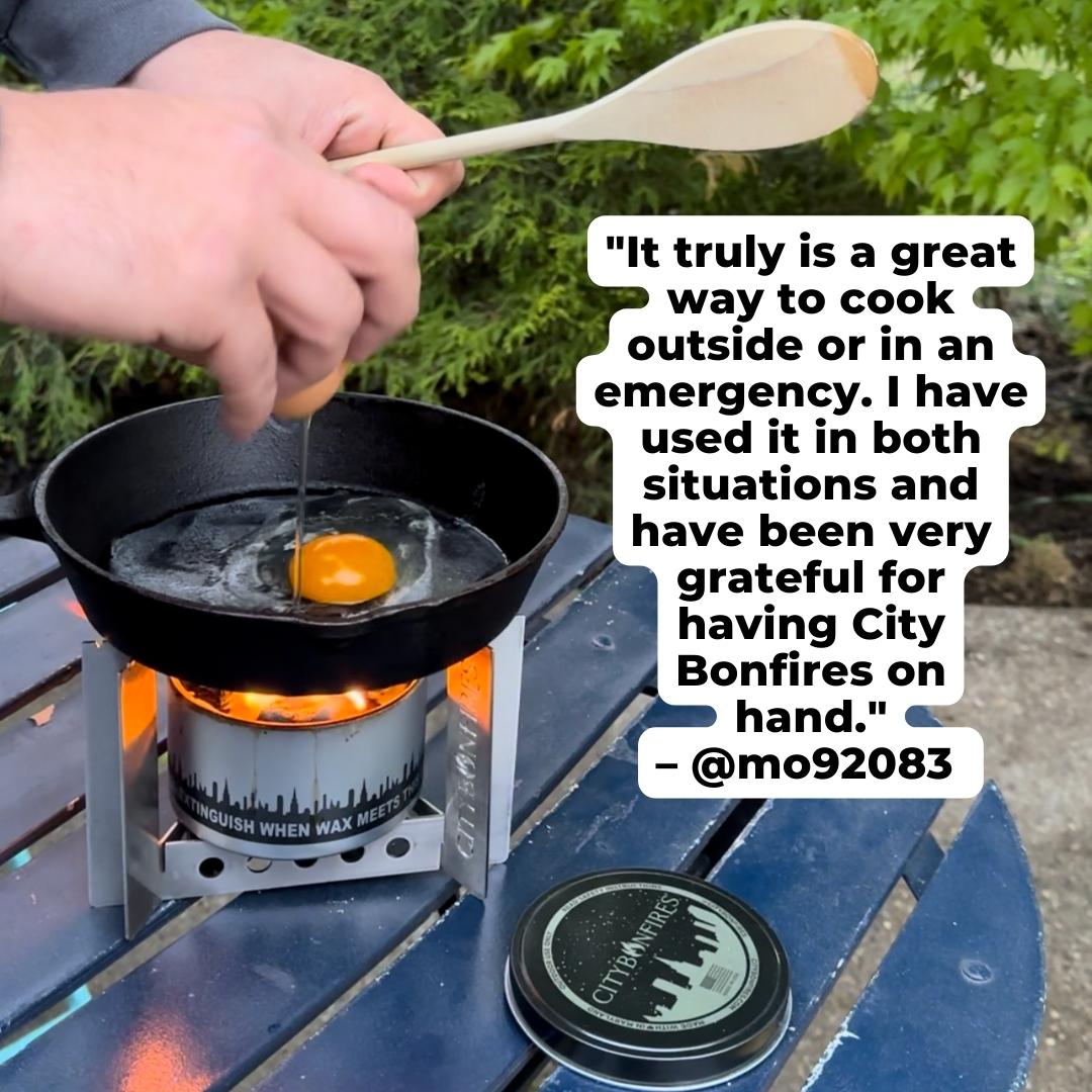 Portable camp stove with skillet and egg over open flame, with fuel canister nearby