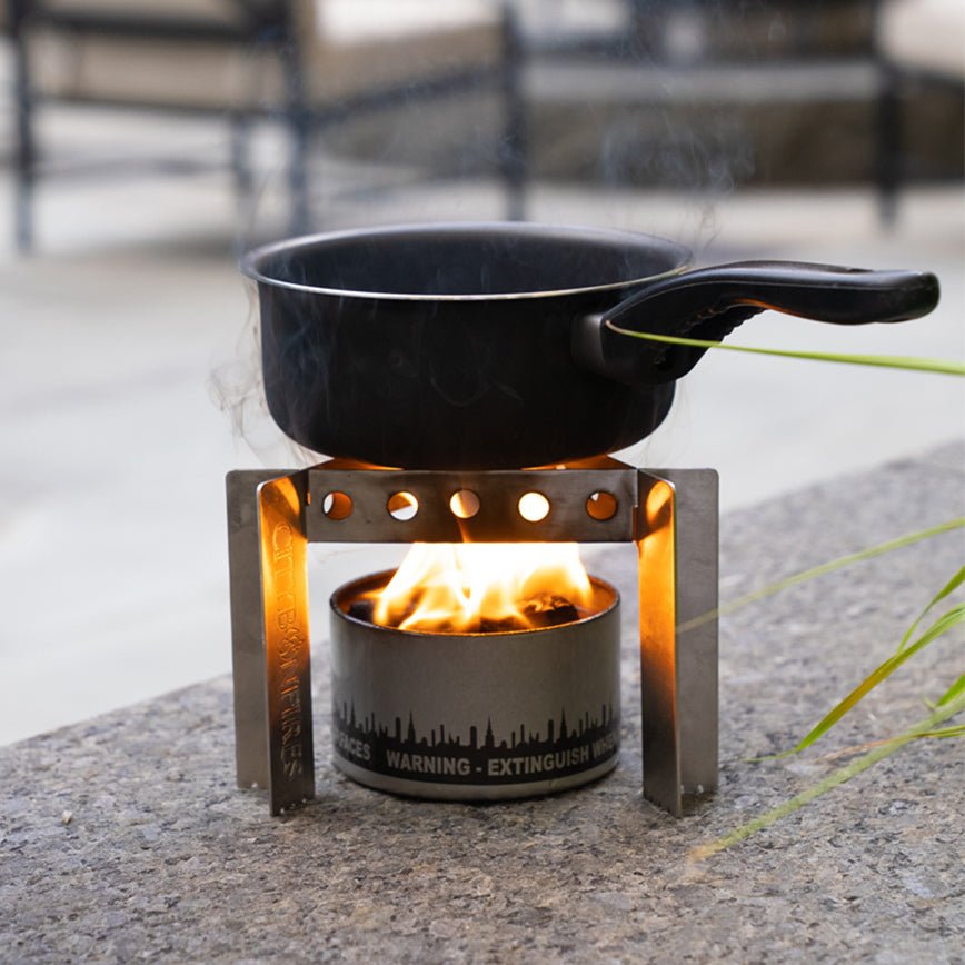 Portable camp stove with black pot, orange burner and visible flames