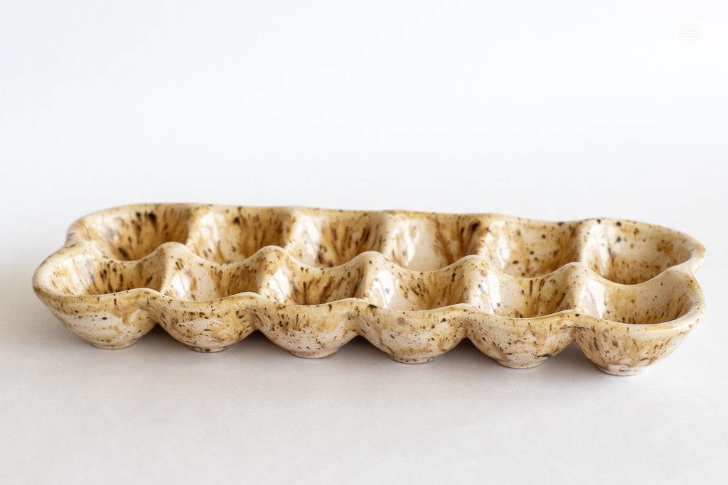 Ceramic egg carton, long row of speckled egg cups in beige with brown flecks