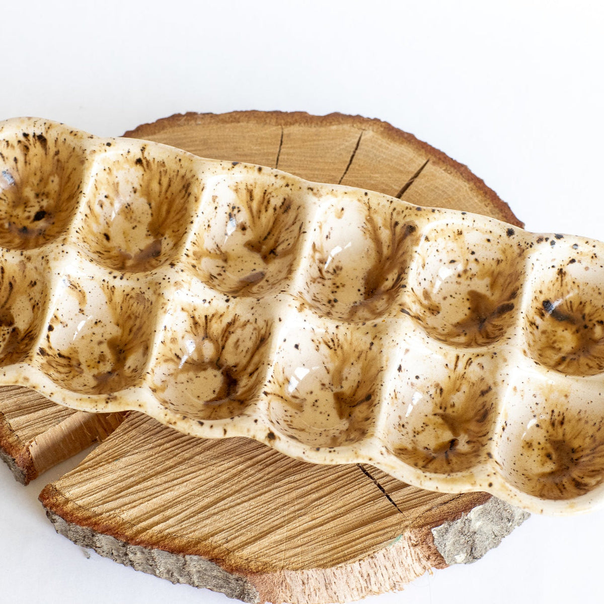 Ceramic egg carton detail: speckled cups on a rustic wooden slice
