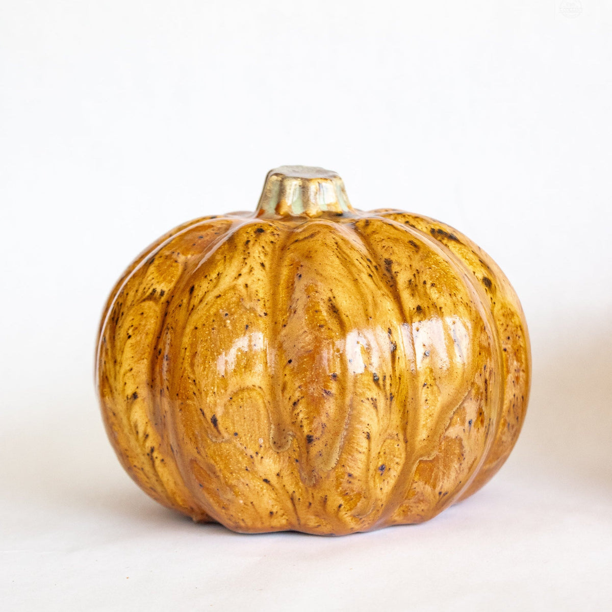Ceramic pumpkin figurine with glossy golden-orange glaze and ribbed texture, short stem
