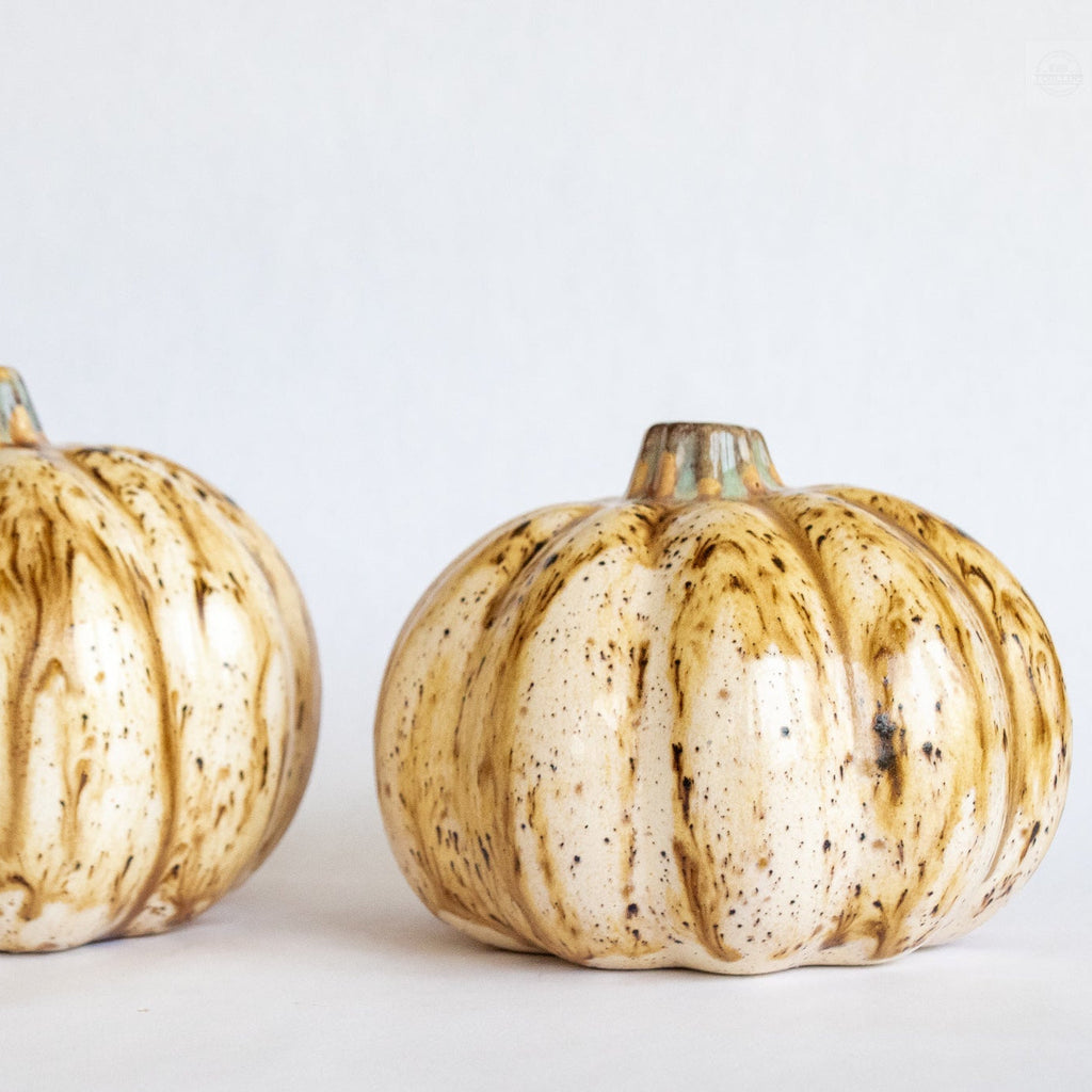 Ceramic pumpkin figurine with beige glaze and speckled vertical ridges, brown stem
