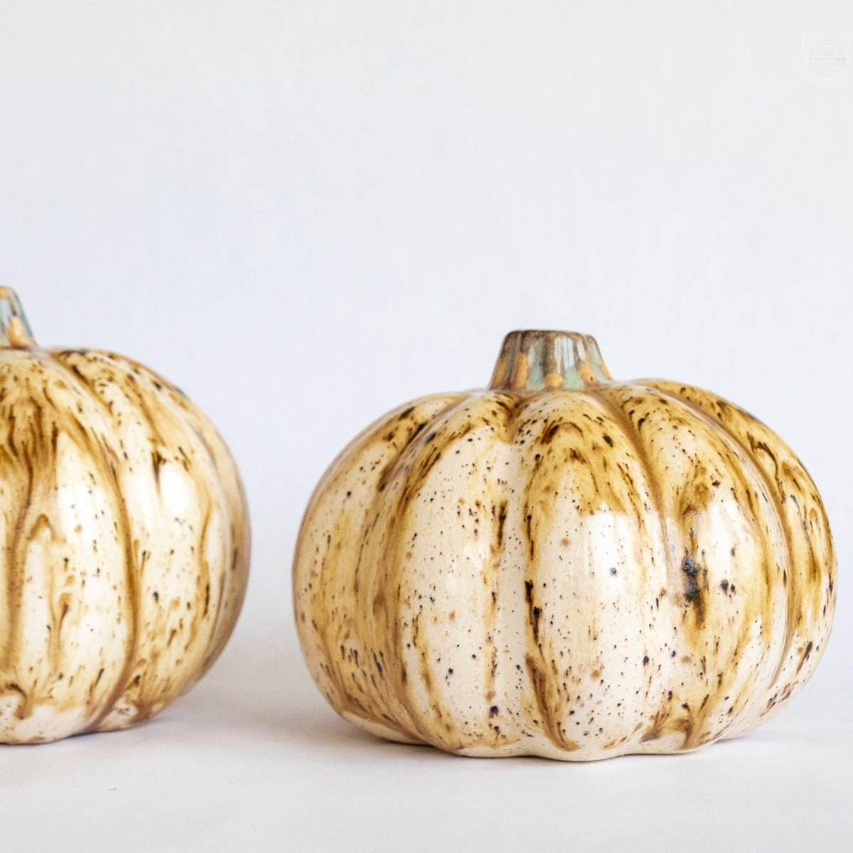 Ceramic pumpkin figurine with beige glaze and speckled vertical ridges, brown stem