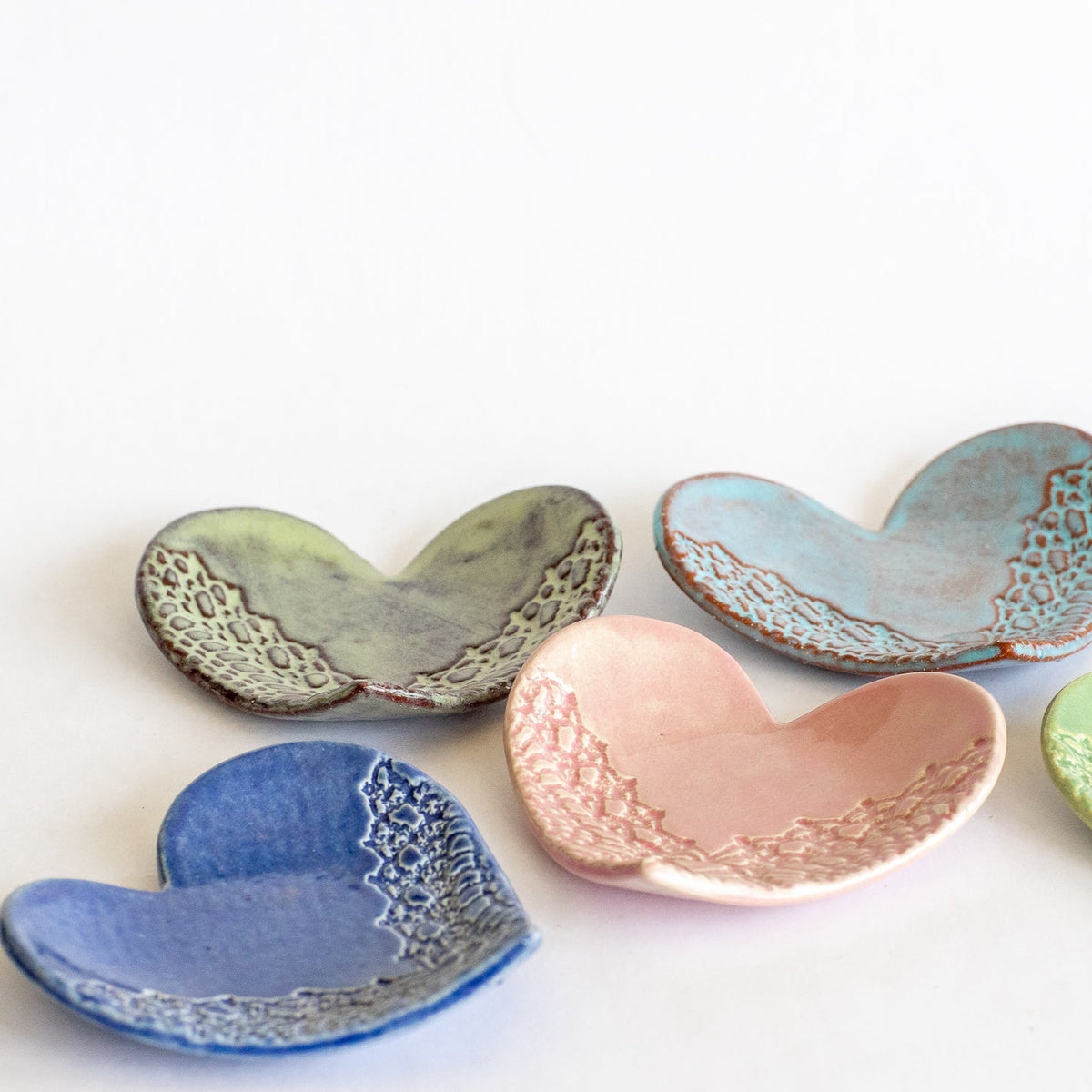 Heart-shaped ring dishes in green, blue, and pink with raised lace-like textured pattern