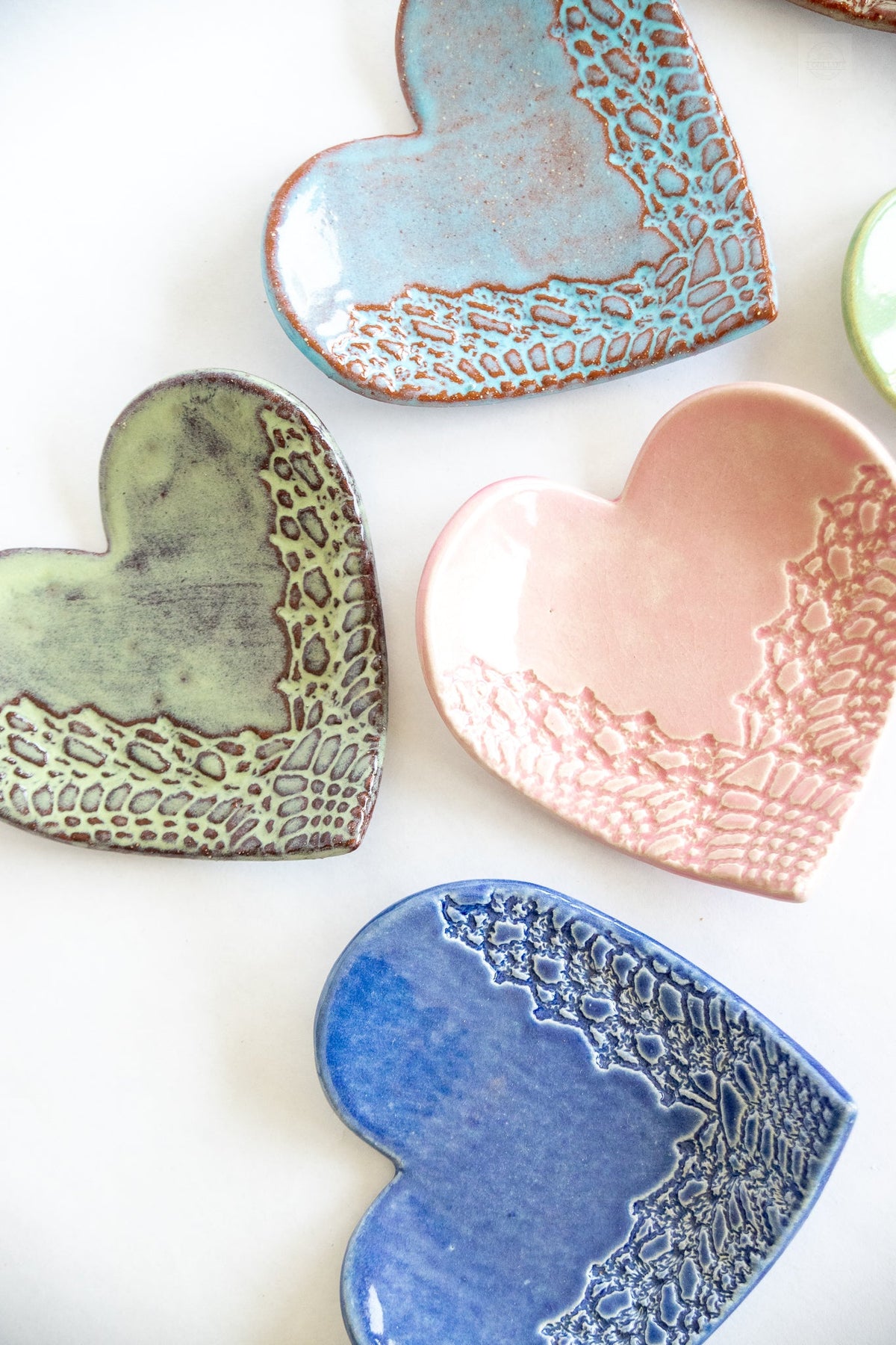 Stacked and paired heart-shaped ring dishes in blue, green, and pink with textured sides