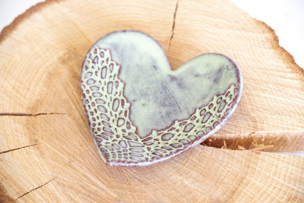 Single heart-shaped ring dish in pale blue-gray with textured lace pattern on wood