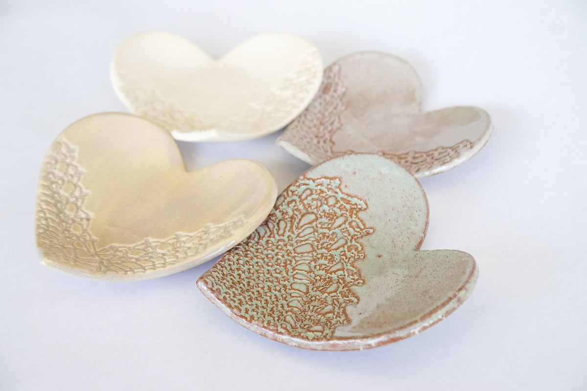 Multiple heart-shaped ring dishes in cream and beige with textured interior and wavy rim