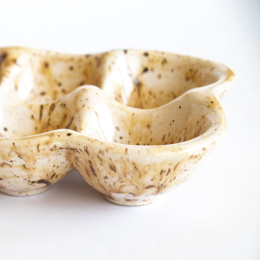 Ceramic egg carton, side view of speckled cups in beige with dark brown