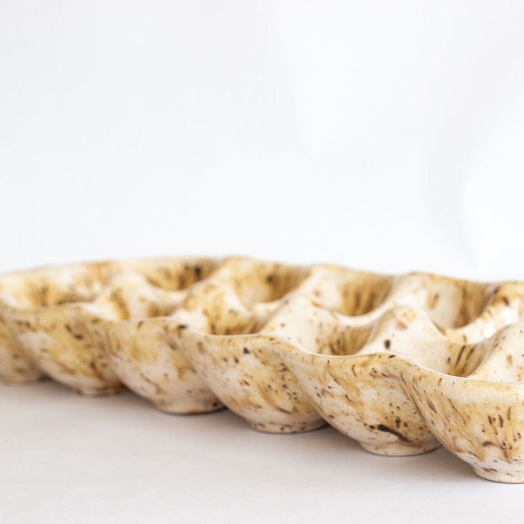 Ceramic egg carton with row of speckled egg cups, beige glaze with brown flecks