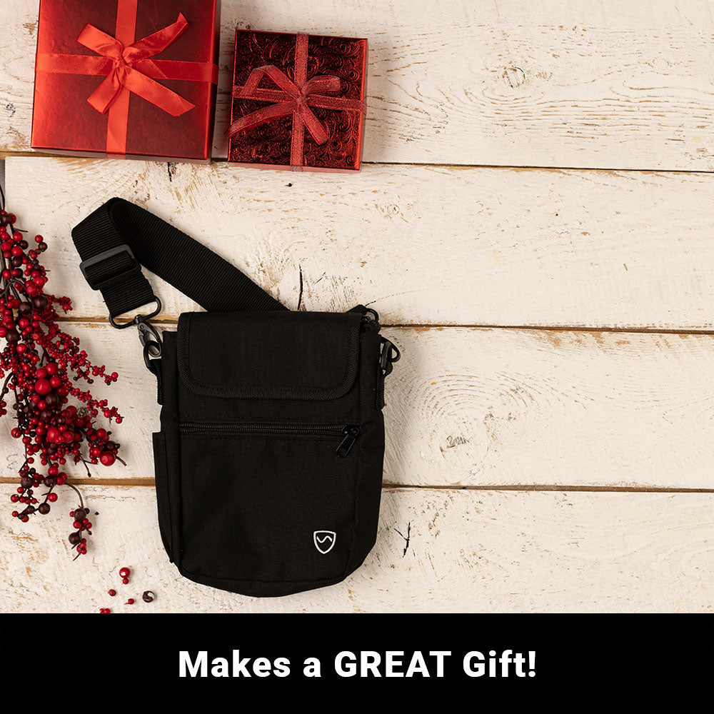 Black phone pouch with crossbody strap and front flap, placed on table