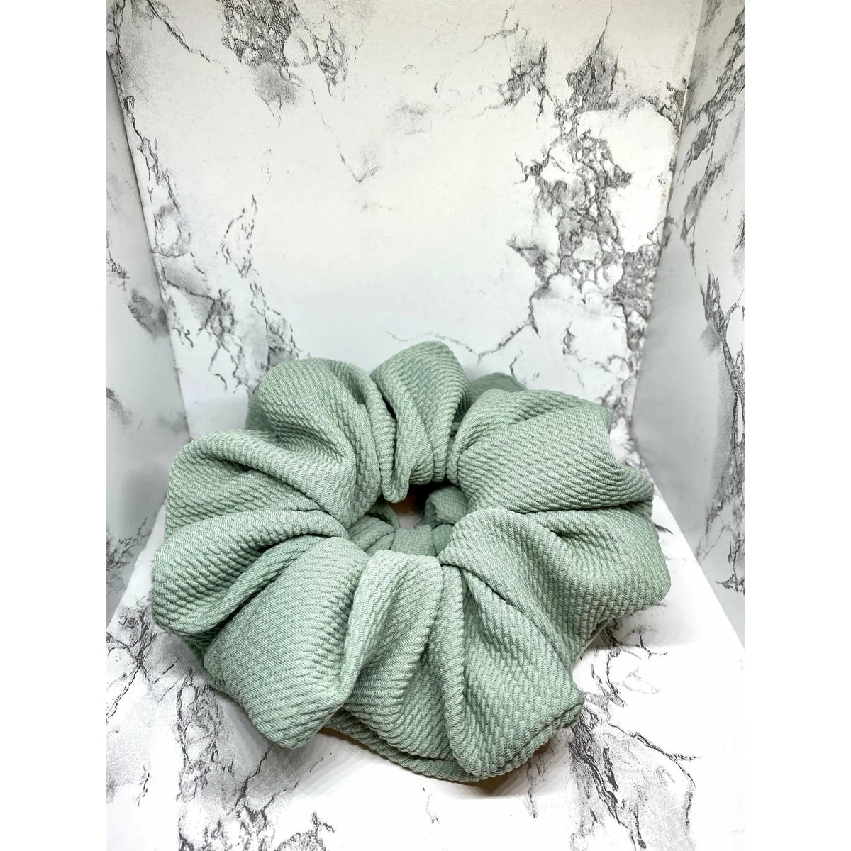 Sage green fabric scrunchie with thick gathered center and layered loops