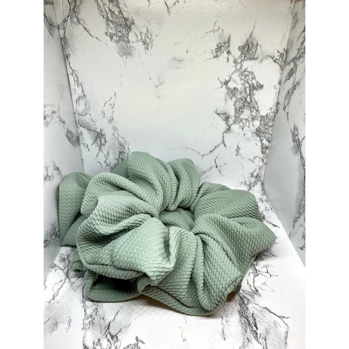 Sage green scrunchie with large bow-like knot and stitched gathers