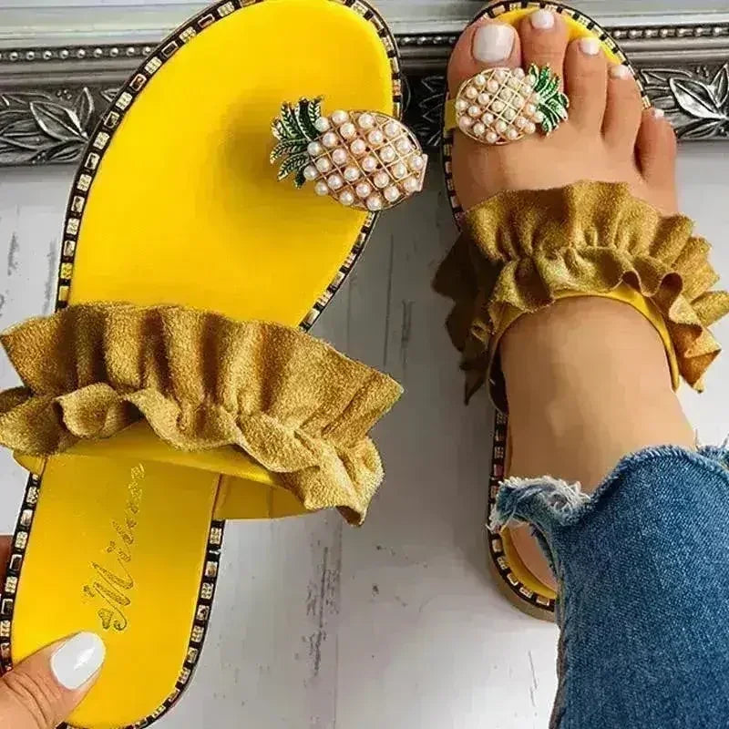 Yellow flat slide sandals with pearl pineapple embellishment and ruffled strap