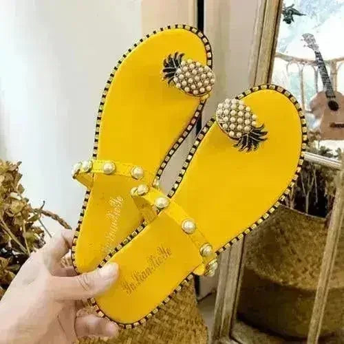 Yellow flat slide sandals with pearl pineapple embellishment and bead-dotted thong strap