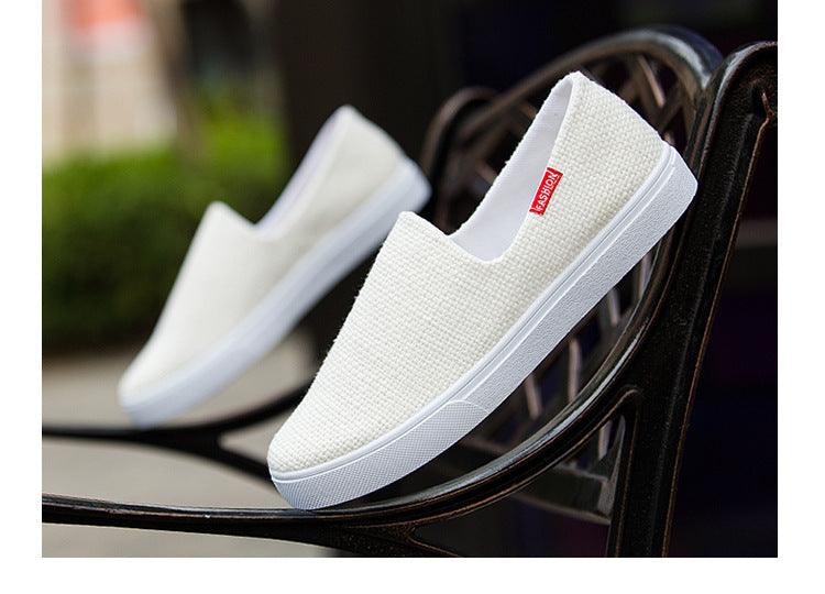 White canvas slip-on sneakers with textured upper and sidewall sole