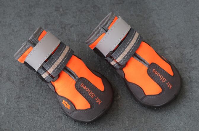 Two orange and black waterproof dog boots with gray straps and hook-and-loop closure