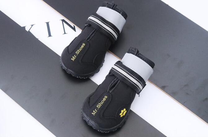 Pair of black waterproof dog boots with white cuff bands and paw-mark details