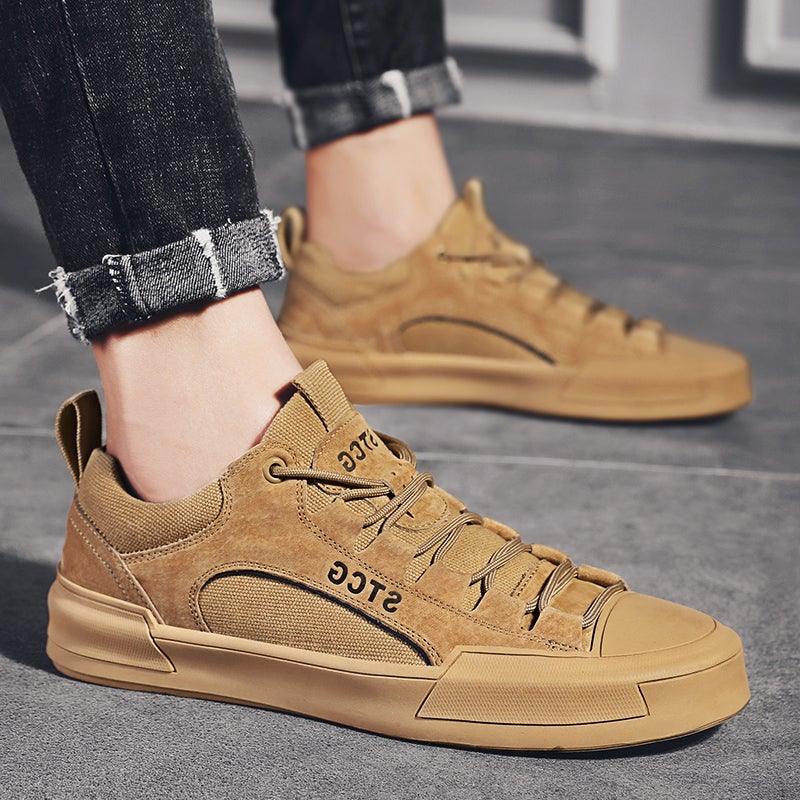 Tan lace-up sneakers with textured upper and rubber outsole, worn with cuffed jeans