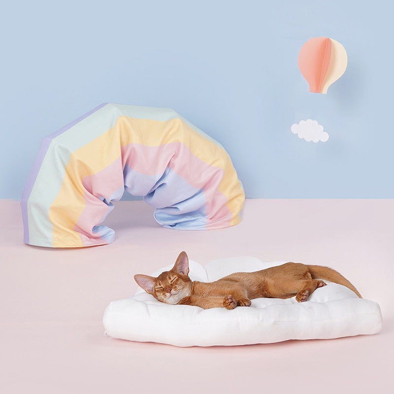 Collapsible cat tunnel tube with soft cushion, pastel pink-and-blue fabric, resting cat