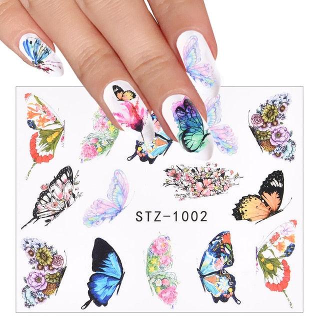 Hands with butterfly nail art transfer decals featuring multicolor wings on nails