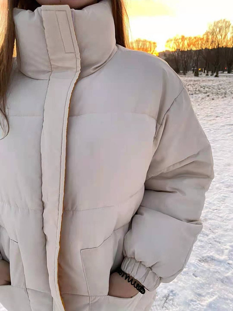 Light beige padded jacket close-up with high collar, full zipper, and elastic cuff