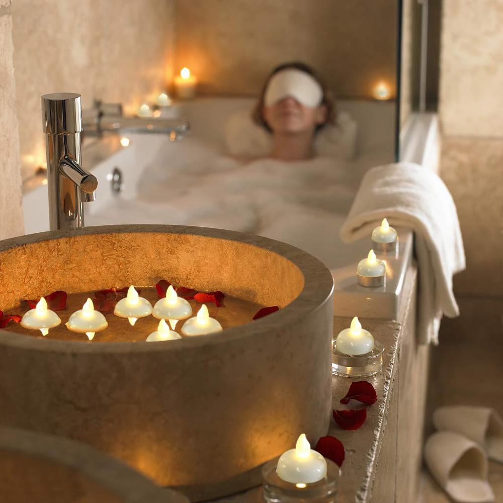 LED floating tea lights in a round tub with warm yellow flames near spa