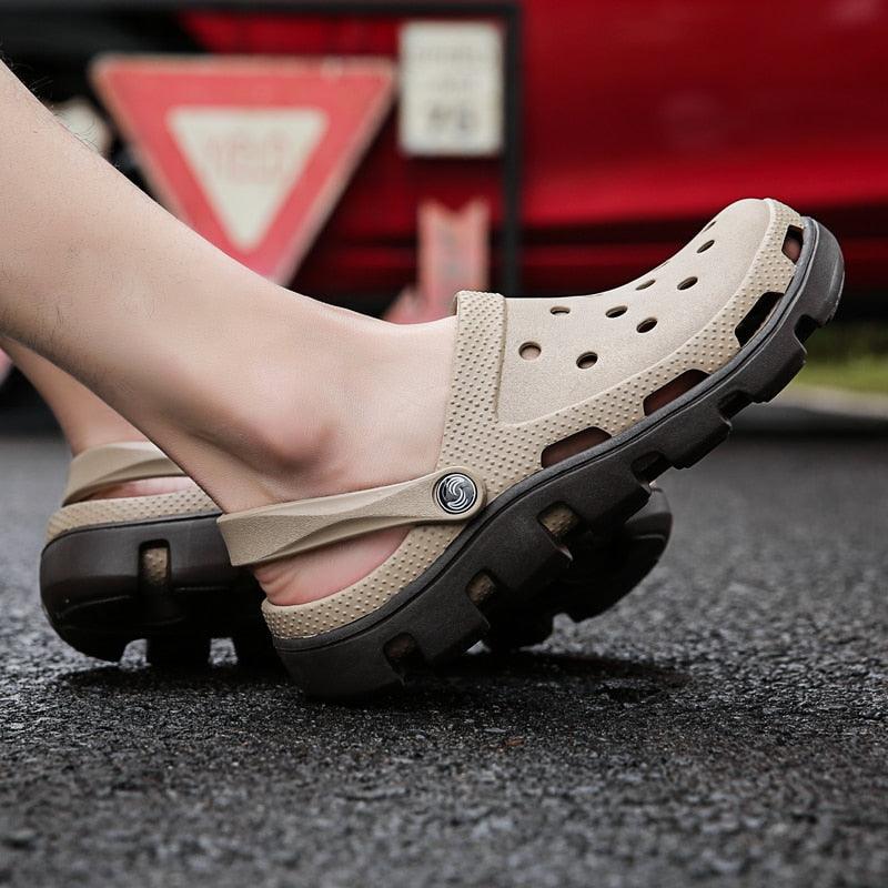 Beige men’s slide clogs with side strap, perforated top, and thick black outsole
