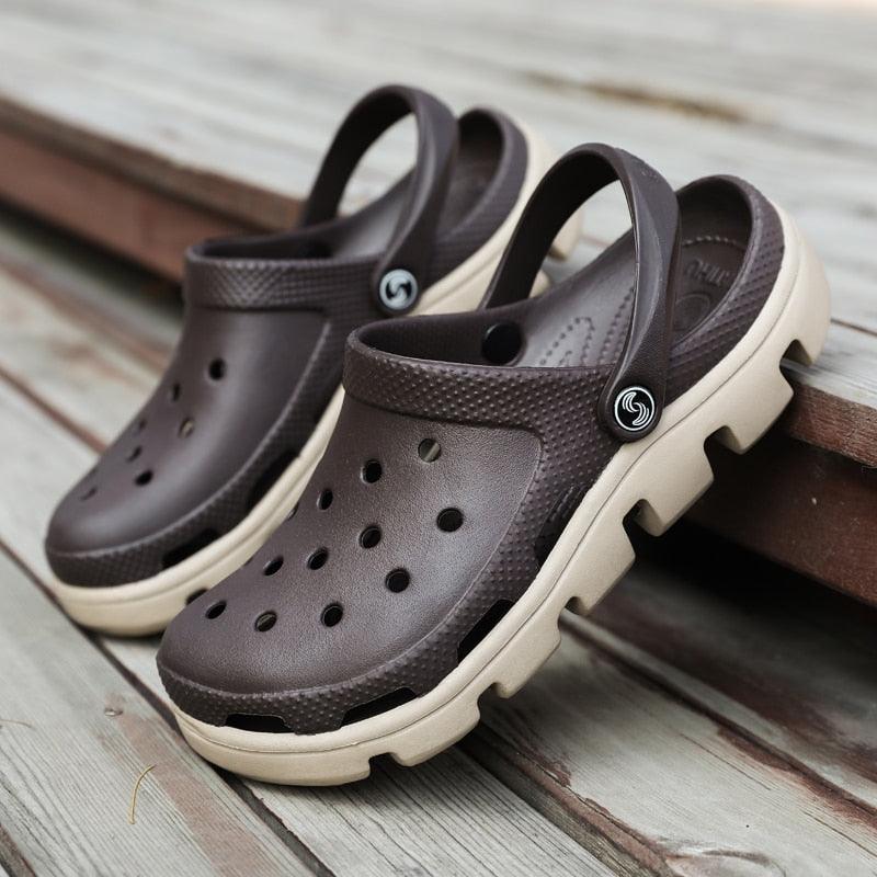 Brown men’s clogs with perforated upper, adjustable strap, and cream/black sole