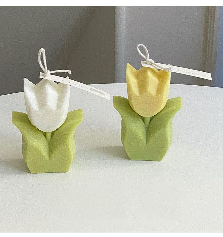 Two tulip-shaped flower candles: white and yellow tops on green bases.