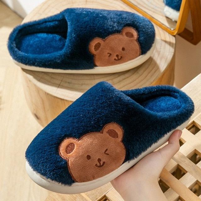 Blue plush house slippers with bear face patch and white sole