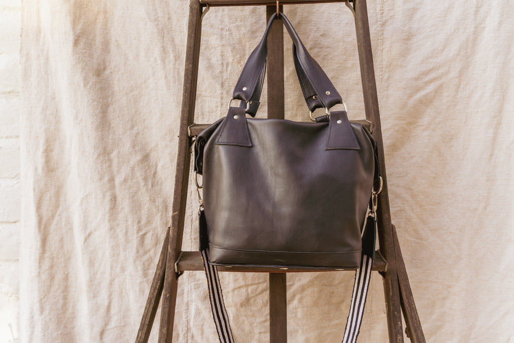 Black leather tote with adjustable shoulder straps and front hardware ring