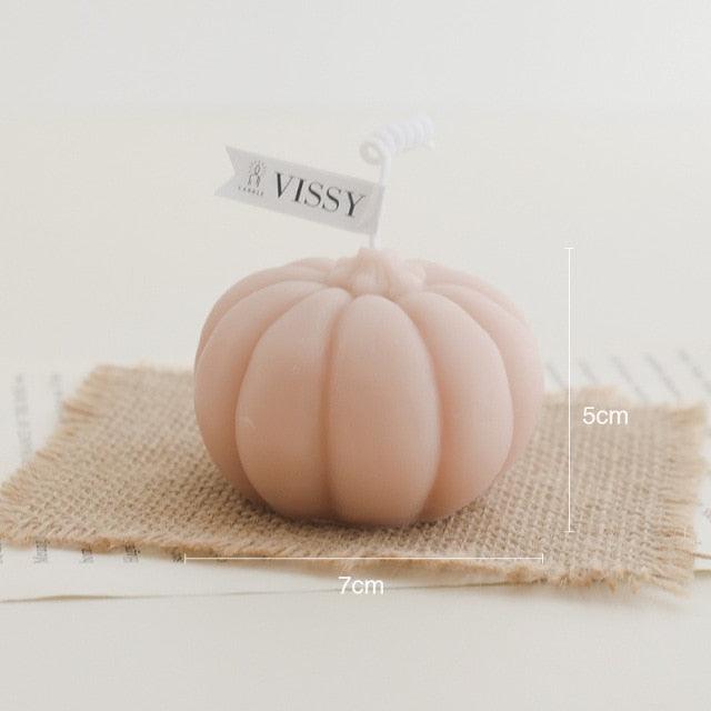 Peach pumpkin-shaped candle on burlap square with VISSY tag