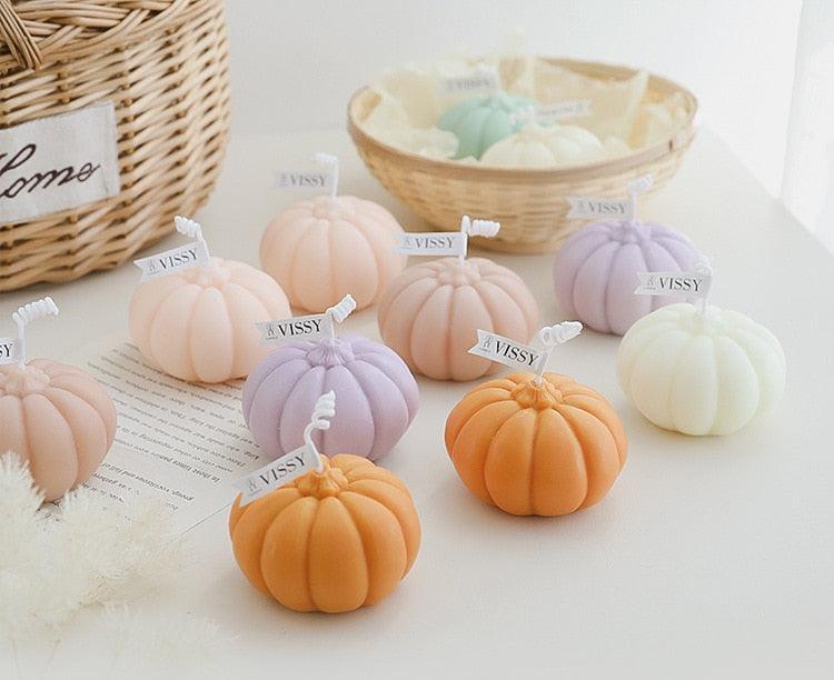 Assorted pumpkin-shaped candles in orange, lavender, white, mint, and pink