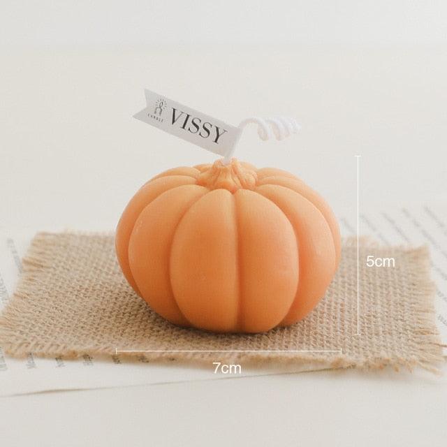 Orange pumpkin-shaped candle on burlap square with VISSY tag