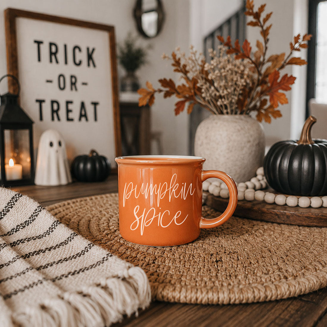 Orange ceramic mug with white “pumpkin spice” script lettering, small handle view