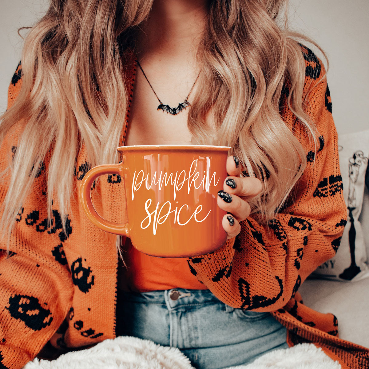 Orange mug held to chest, Pumpkin Spice script lettering on front