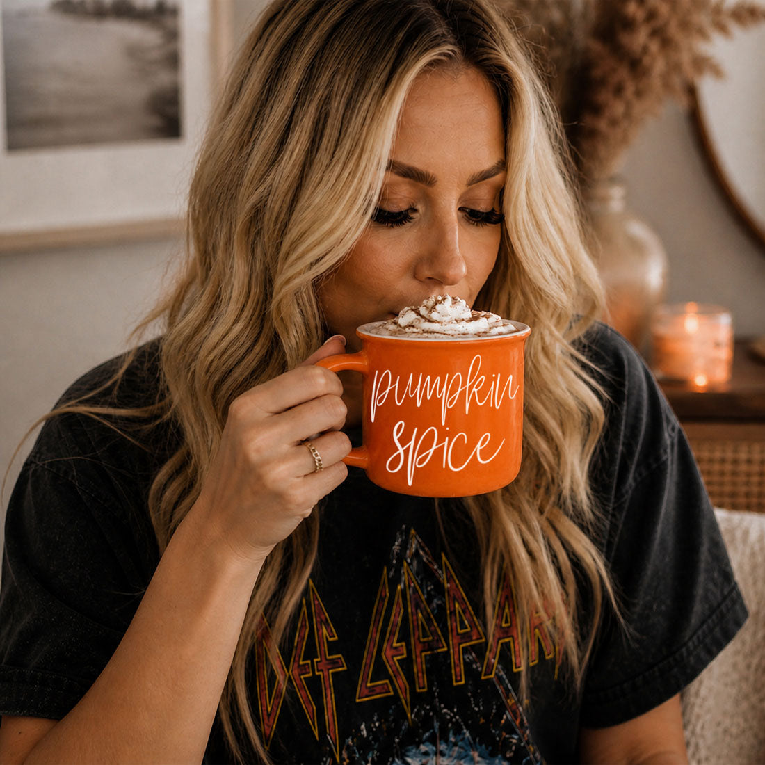 Person sipping from an orange mug with “Pumpkin Spice” script text