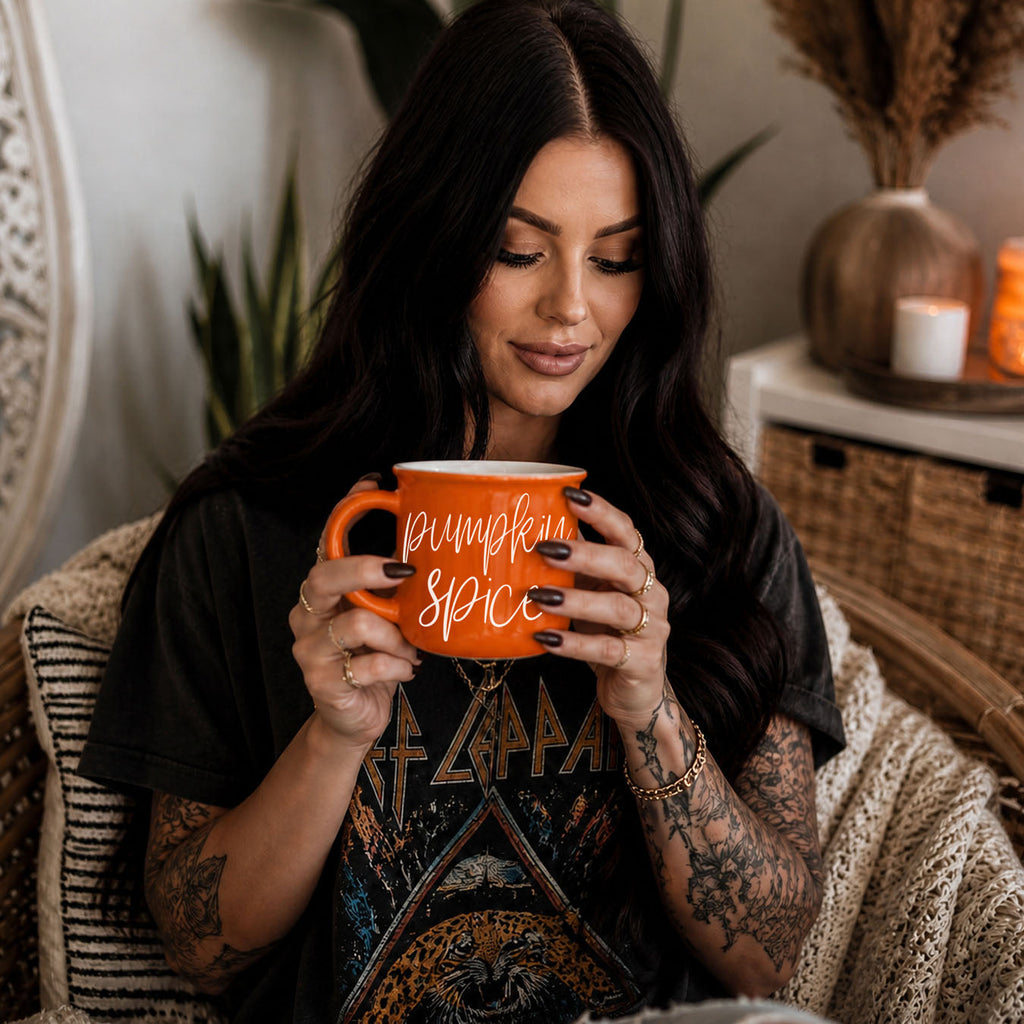 Orange mug with “Pumpkin Spice” script text held in front of a person