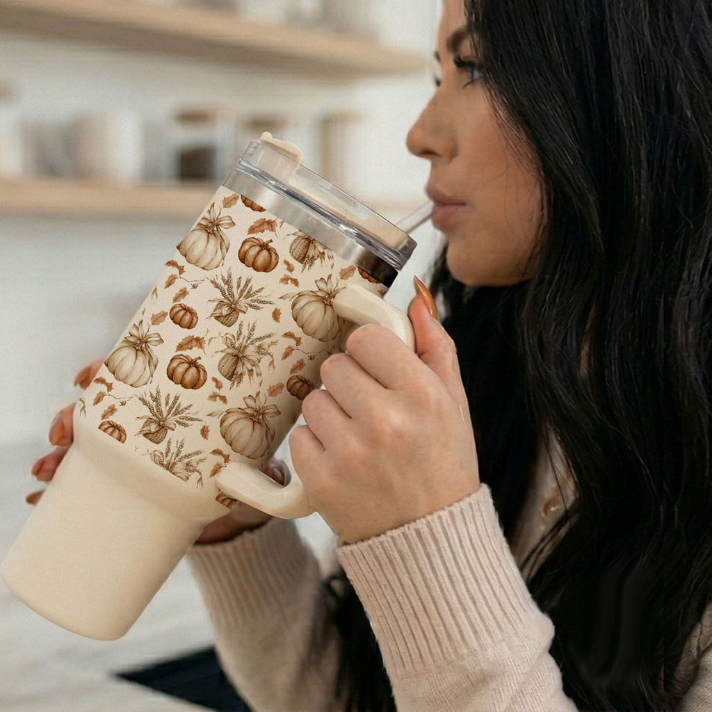 40 oz tumbler held to lips with straw; pumpkin floral design and clear lid