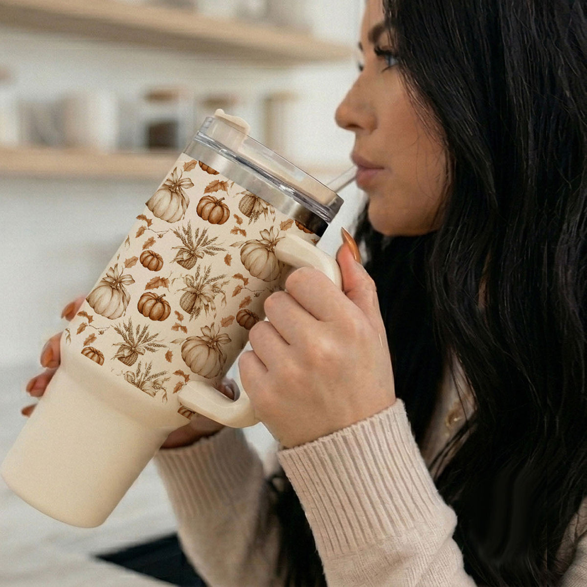40 oz tumbler held to lips with straw; pumpkin floral design and clear lid